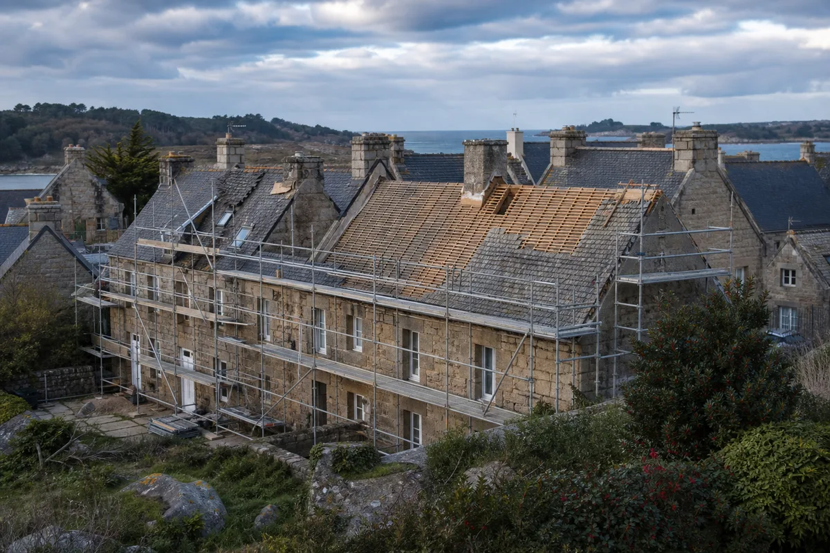 Échafaudage installé le long d&rsquo;une maison en pierre pendant la dépose d&rsquo;une ancienne couverture
